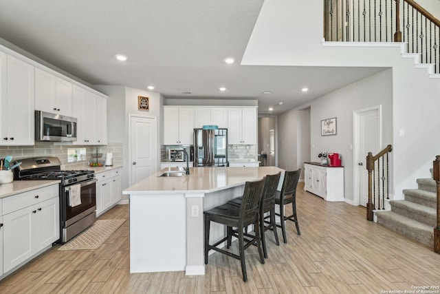 kitchen featuring white cabinets, light wood-type flooring, appliances with stainless steel finishes, and a sink