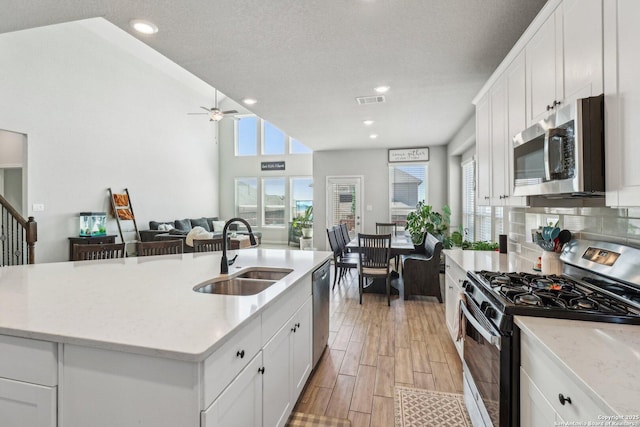 kitchen featuring a sink, light stone counters, white cabinetry, appliances with stainless steel finishes, and wood tiled floor