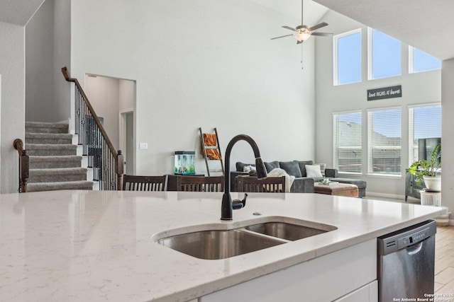 kitchen featuring dishwasher, light stone counters, a healthy amount of sunlight, and a sink