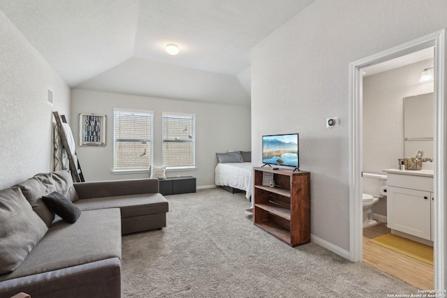 living area with light carpet, visible vents, baseboards, and vaulted ceiling