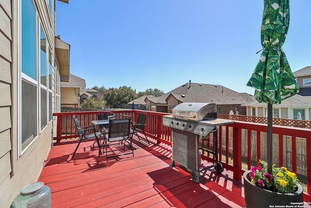 wooden deck featuring a residential view, a grill, outdoor dining space, and fence