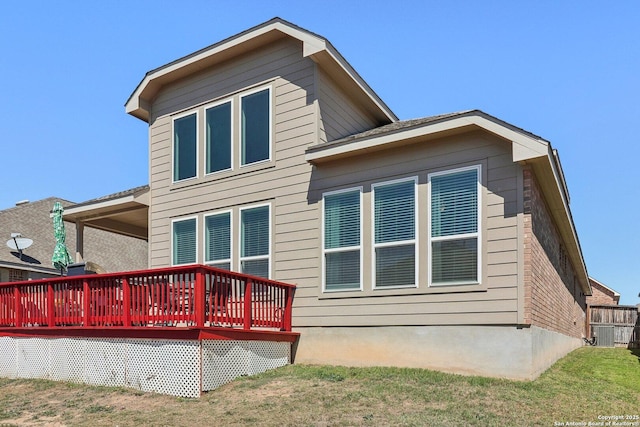 rear view of house featuring a deck, cooling unit, and a lawn