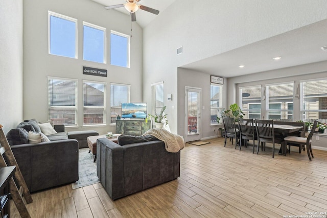 living room featuring visible vents, baseboards, ceiling fan, and light wood finished floors