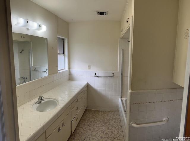 bathroom with visible vents, tile walls, vanity, and a wainscoted wall