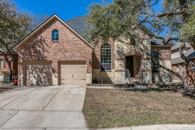 view of front facade with concrete driveway, brick siding, stone siding, and roof with shingles