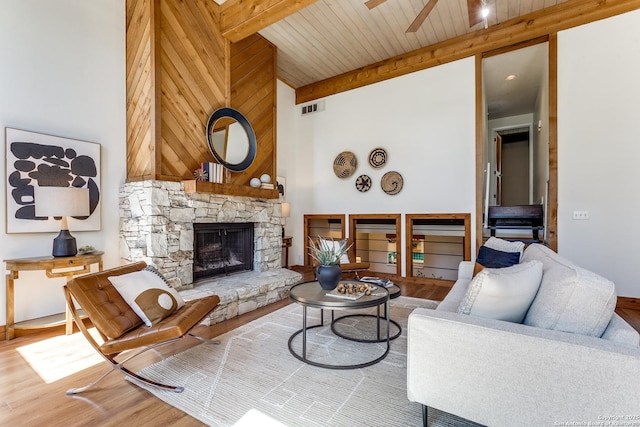 living area featuring visible vents, beamed ceiling, a fireplace, and wood finished floors