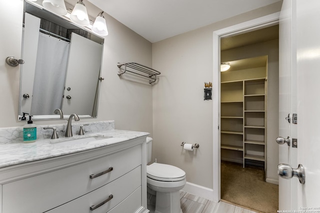 bathroom featuring vanity, toilet, and baseboards