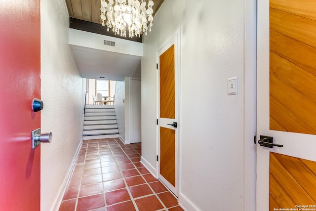 corridor with baseboards, visible vents, an inviting chandelier, stairs, and tile patterned floors