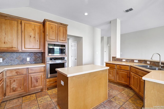 kitchen featuring visible vents, a center island, decorative backsplash, appliances with stainless steel finishes, and a sink