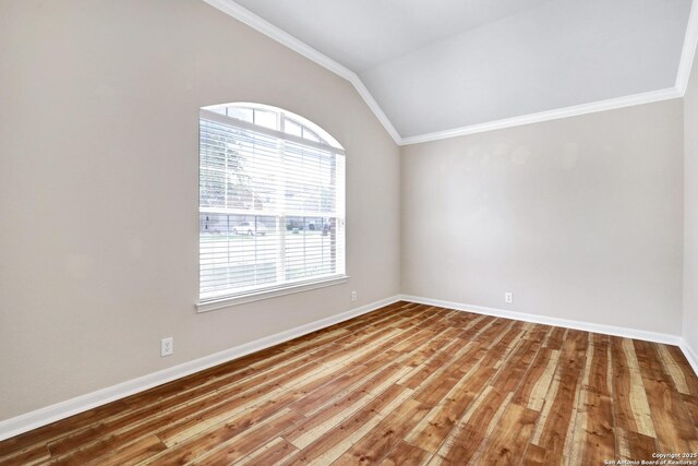 unfurnished room with baseboards, lofted ceiling, wood finished floors, and ornamental molding