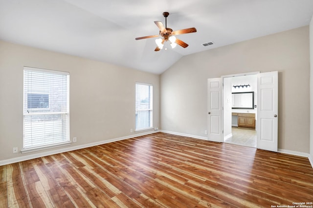 unfurnished room with baseboards, lofted ceiling, and wood finished floors