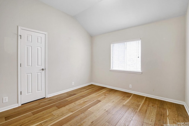 empty room featuring baseboards, light wood-type flooring, and lofted ceiling