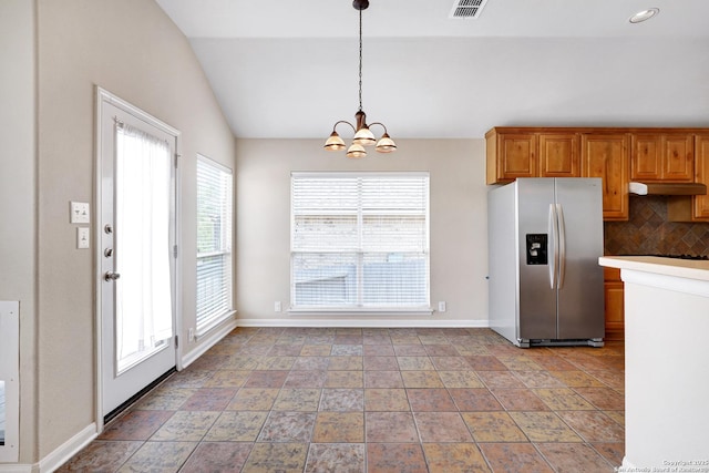 kitchen featuring brown cabinetry, visible vents, lofted ceiling, stainless steel refrigerator with ice dispenser, and tasteful backsplash