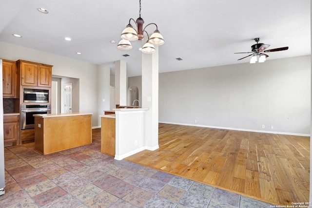 kitchen featuring stainless steel appliances, baseboards, open floor plan, and light countertops