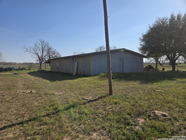 view of side of property with a rural view, fence, a yard, a pole building, and an outbuilding