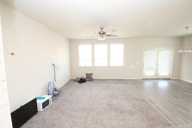 interior space featuring ceiling fan with notable chandelier, wood finished floors, and baseboards