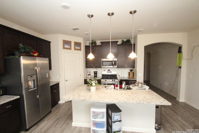 kitchen featuring visible vents, backsplash, light wood-style flooring, appliances with stainless steel finishes, and arched walkways