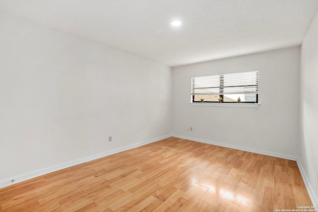 empty room with a textured ceiling, baseboards, and wood finished floors