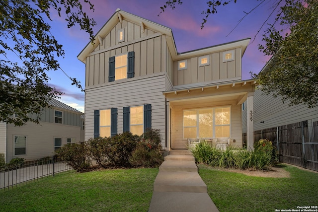 view of front of property with a porch, board and batten siding, a yard, and fence