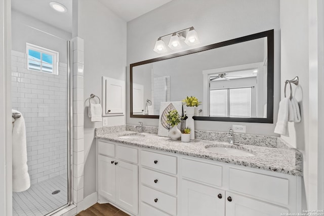 bathroom featuring a sink, a ceiling fan, double vanity, and a shower stall