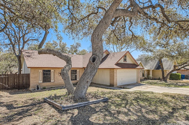 view of front of home with brick siding, an attached garage, concrete driveway, and fence