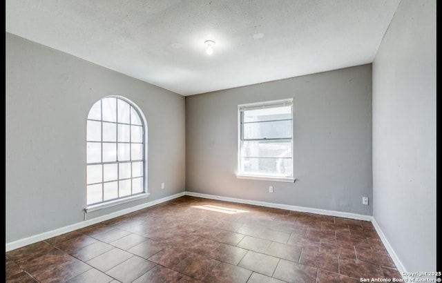 spare room with a wealth of natural light and baseboards