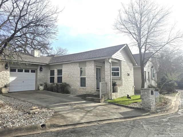 ranch-style home featuring a shingled roof, concrete driveway, an attached garage, and a chimney