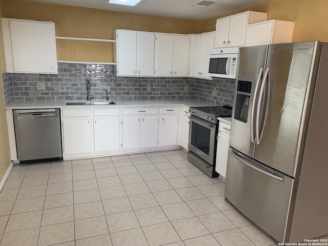 kitchen featuring tasteful backsplash, light countertops, appliances with stainless steel finishes, white cabinets, and a sink