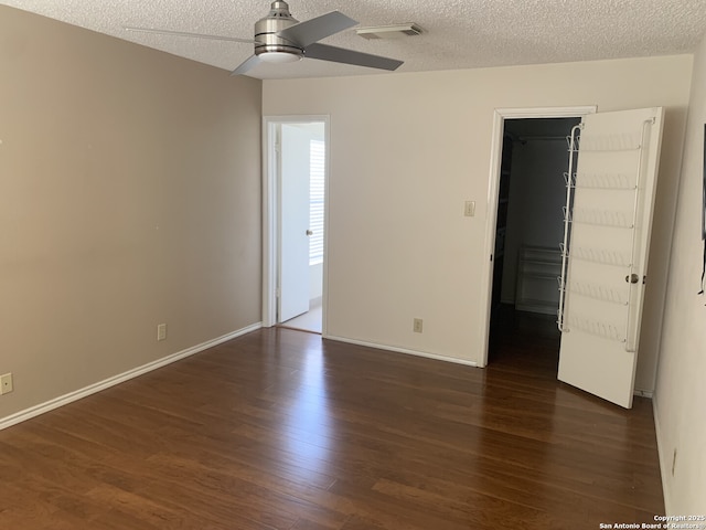 unfurnished room featuring visible vents, dark wood-type flooring, a textured ceiling, baseboards, and ceiling fan