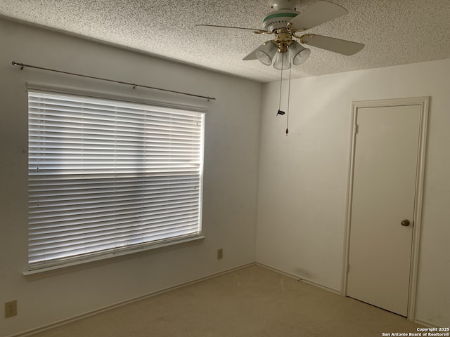 unfurnished room with ceiling fan and a textured ceiling