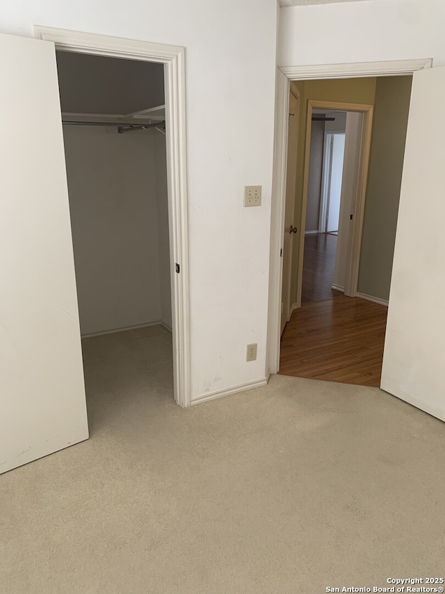 unfurnished bedroom featuring a closet, a walk in closet, and carpet