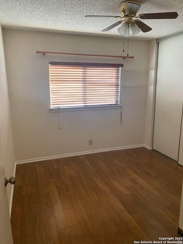 empty room with a ceiling fan, wood finished floors, baseboards, and a textured ceiling