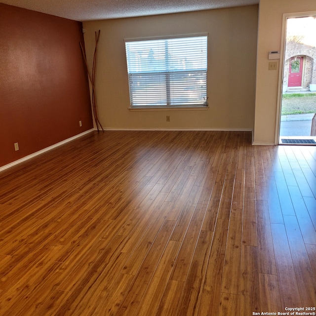 empty room with baseboards and wood finished floors