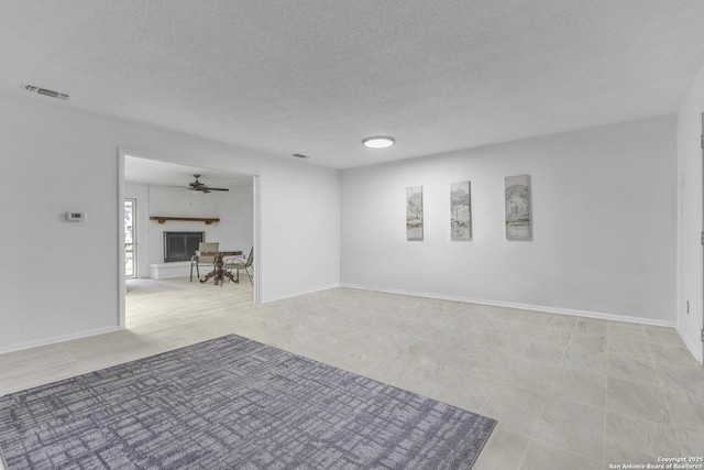 unfurnished room with visible vents, a fireplace, a textured ceiling, and baseboards