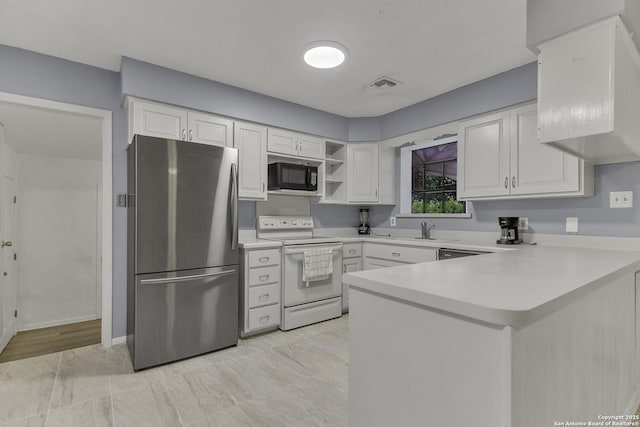 kitchen featuring visible vents, white electric range oven, freestanding refrigerator, a peninsula, and black microwave