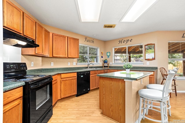 kitchen with visible vents, a sink, black appliances, under cabinet range hood, and light wood-type flooring