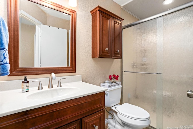 full bath featuring a textured wall, vanity, a shower stall, and toilet