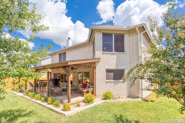 back of property with a lawn, a ceiling fan, a patio, brick siding, and a chimney