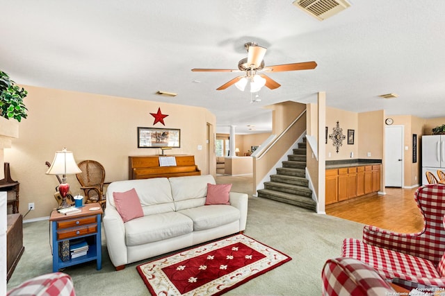 living room featuring visible vents, baseboards, stairs, and a ceiling fan