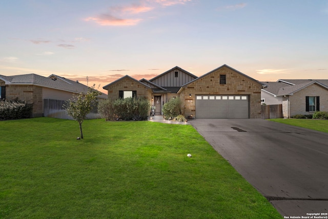 view of front of property featuring board and batten siding, fence, a garage, a yard, and driveway