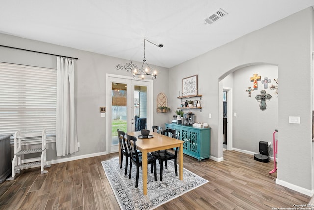 dining room featuring visible vents, arched walkways, baseboards, and wood finished floors