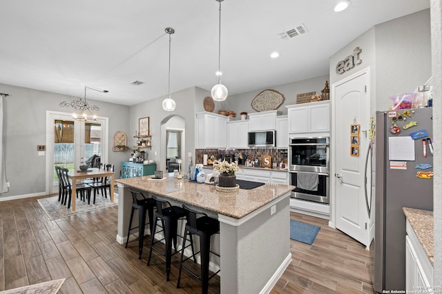 kitchen with visible vents, backsplash, wood finished floors, stainless steel appliances, and arched walkways