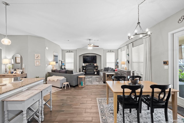 dining area featuring arched walkways, ceiling fan with notable chandelier, and dark wood-style flooring