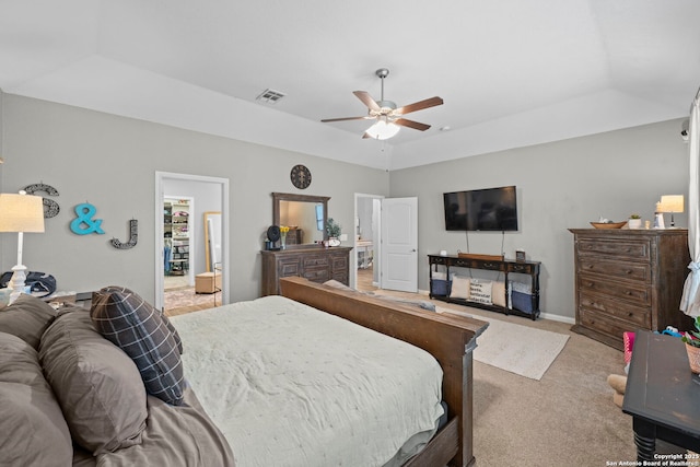 bedroom with visible vents, baseboards, a tray ceiling, light carpet, and a ceiling fan