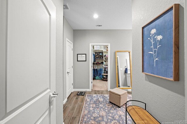 hall featuring recessed lighting, visible vents, wood tiled floor, and a textured wall