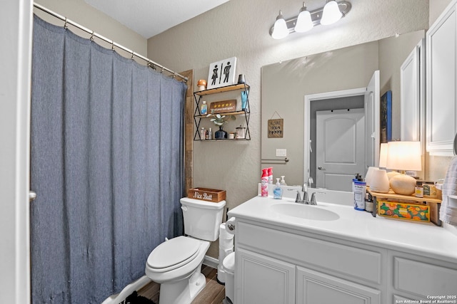 bathroom featuring a shower with curtain, toilet, vanity, and a textured wall