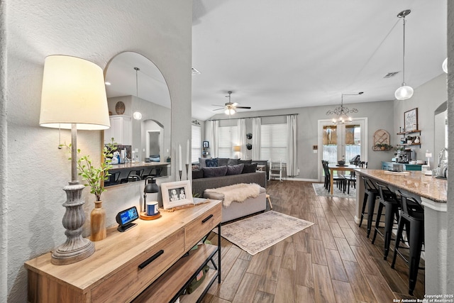 living area with visible vents, baseboards, a ceiling fan, and dark wood-style flooring