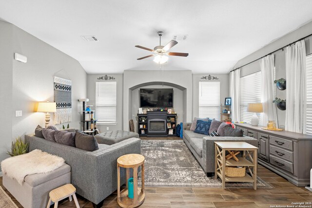 living room featuring vaulted ceiling, a glass covered fireplace, plenty of natural light, and wood tiled floor