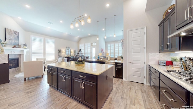 kitchen with light wood-style flooring, open floor plan, a fireplace, and vaulted ceiling