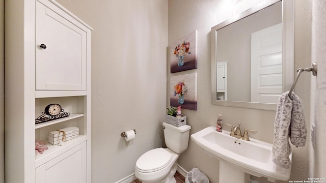 bathroom with a sink, baseboards, toilet, and built in shelves